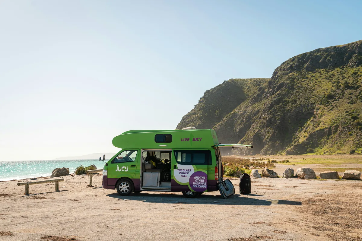 JUCY campervan on the beach with doors open
